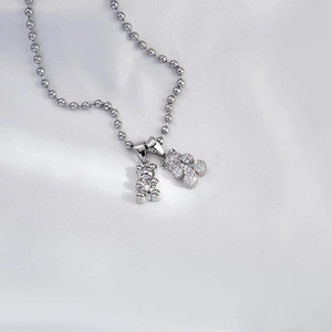 Detailed view of silver ball chain necklace featuring dual teddy bear charms with pavé stones