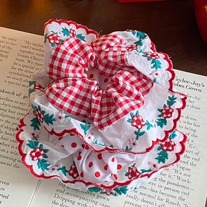 Floral plaid hair scrunchie with lace edges on a book over a dark wood background