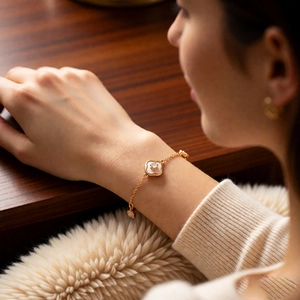 Détail du bracelet trèfle plaqué or 18 carats avec nacre blanche sur le poignet féminin