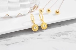 Detailed close-up of gold-plated evil eye earrings with a sparkling zircon inlay detail
