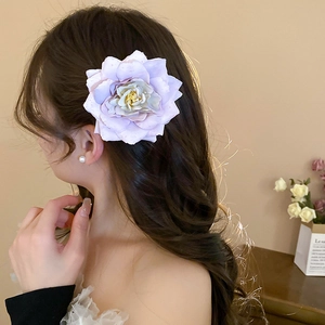Close-up of a large lavender fabric rose hair clip worn elegantly on wavy hair