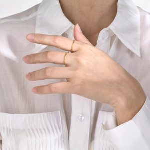 Detail of minimalist gold-plated chain-textured rings worn in a stack for styling