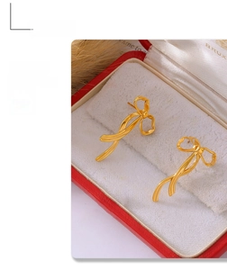Nahaufnahme von goldenen Schleifenohrringen in einer roten Schmuckschatulle mit Samtfutter