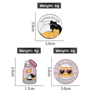 Detailed view of three cute cartoon cat enamel pins with various witty slogans and weights