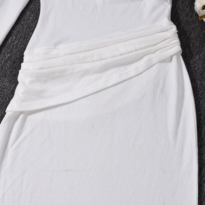 Gros plan sur les fronces latérales et les détails plissés de la robe en tricot blanc