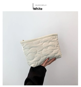 Detail of white quilted cosmetic bag with large floral stitching and gold zipper