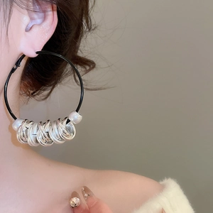 Detail of twisted leather cord earrings with silver rings and white pearls on a female model