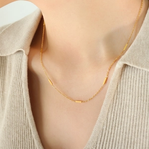 Minimalist gold chain necklace featuring five sleek rectangular bars worn on neck