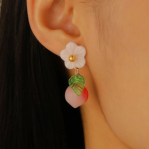 Detail of peach fruit drop earrings with white flower and green leaf on ear