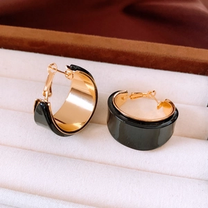 Detail of vintage 18K gold plated C-shape hoop earrings with black resin inlay