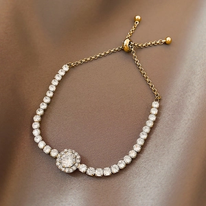 Detail of adjustable gold slider bracelet with sparkling zircons on silk background