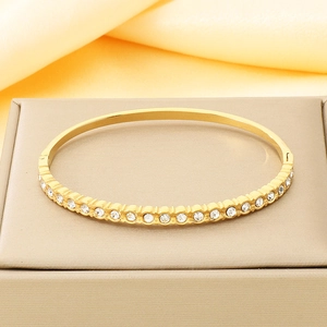 Détail macro d'un bracelet doré à charnière orné de zircons circulaires sur cuir