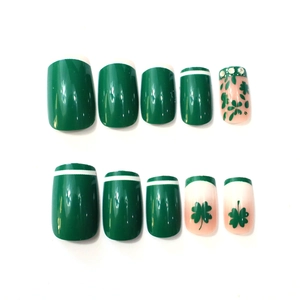 Detail of green clover press-on nails with white French tips and crystal rhinestones