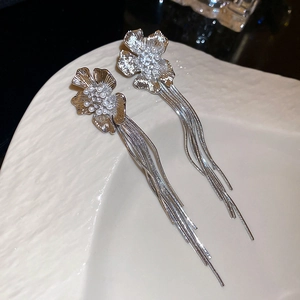 Close-up of silver flower earrings with zircon pearls and elegant long metal tassels