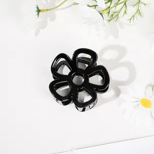 Detail of high-gloss black flower hair claw with silver metal spring on white floral background