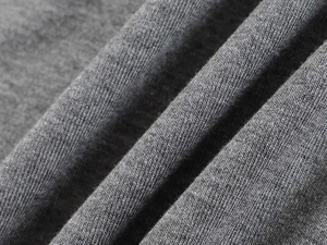 Macro shot of grey knitted fabric texture showing soft fiber weave for V-neck T-shirt