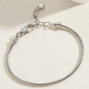 Detailed view of silver snake chain bracelet with heart charm and lobster clasp