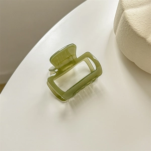 Close-up of green acetate hair claw clip featuring Creation France text on a white surface
