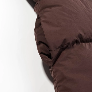 Detailed close-up of brown quilted parka side pocket with premium stitching and texture