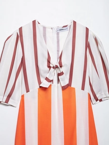 Detail of V-neck tie-knot and puff sleeves on a striped slimming sundress with logo label