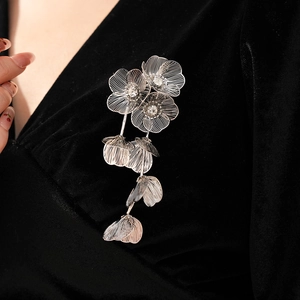 Detail of silver floral tassel brooch with rhinestones on black velvet fabric