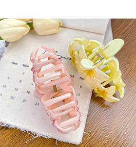 Close-up of pink and yellow candy-colored flower claw clips on a wooden tabletop