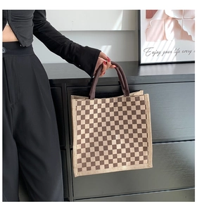 Detail of a brown checkered linen tote bag with sturdy handles and vintage canvas texture
