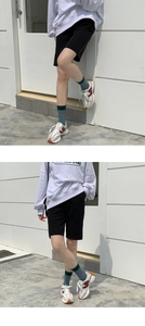 Detail of green striped crew socks styled with black shorts and white sneakers