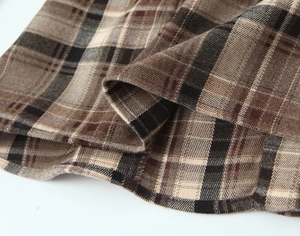 Vue macro de la texture à carreaux marron et coutures de précision sur l'ourlet