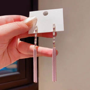 Elegant gold tassel earrings with purple zircon stones shown held in hand