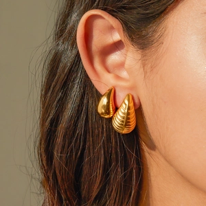 Close-up of gold stainless steel striped teardrop earrings worn by a model