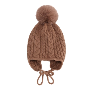 Detail of coffee brown cable knit baby winter hat with large faux fur pom and earflaps