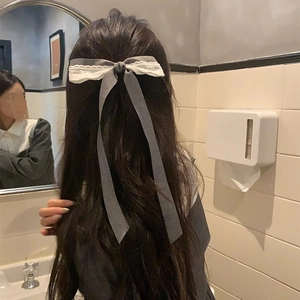 Detailed back view of a grey lace bow hair clip with ribbons on long wavy hair