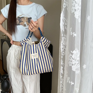 Close-up of quilted striped tote bag with vertical blue and yellow fabric patterns