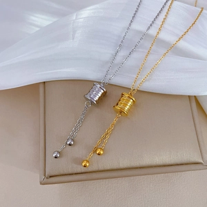 Detail of gold and silver cylinder pendant necklaces with tassels on jewelry box
