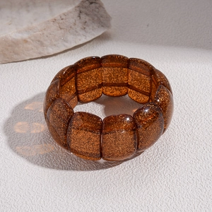 Close-up of brown amber-toned acrylic bead bracelet with golden glitter and elastic cord