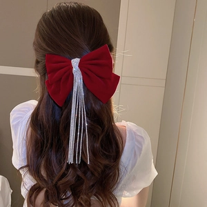 Detail view of burgundy velvet bow hair clip with sparkling rhinestone long tassels on wavy hair