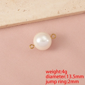 Macro di un ciondolo a perla bianca da 13,5mm con anelli dorati su tessuto rosa