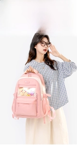 Detail of pink nylon school backpack featuring a transparent window pocket and star charm