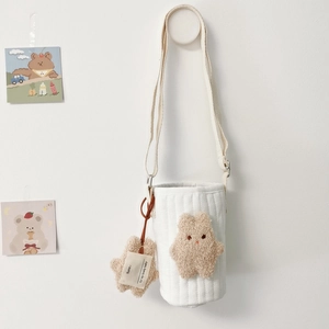 Close-up of quilted fabric cup holder with embroidered bear and star-shaped name tag