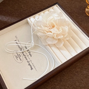 Detail of wooden jewelry tray with beige velvet lining and decorative flower display