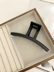 Detailed close-up of a large black matte geometric hair claw clip on a soft fabric display