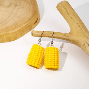 Creative resin corn drop earrings in bright yellow hanging on a natural wooden branch