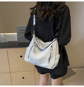 Detailed view of grey tote bag on model showing soft textured leather and zipper details