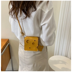 Mini cheese-shaped crossbody bag shown on model highlighting its unique hole design