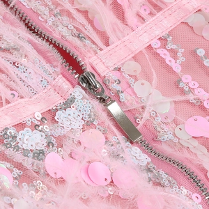 Detailed macro view of pink sequin fabric with soft feather trim and a hidden metal zipper