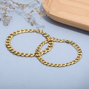 Detaillierte Ansicht von zwei polierten goldenen Panzerarmbändern mit Karabinern auf Tablett