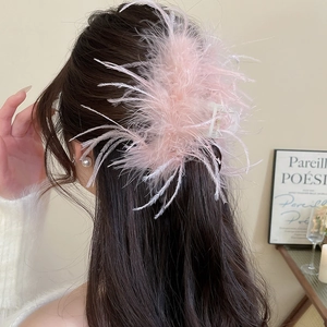 Detail showing plush pink ostrich feathers on a translucent hair claw for elegant styling