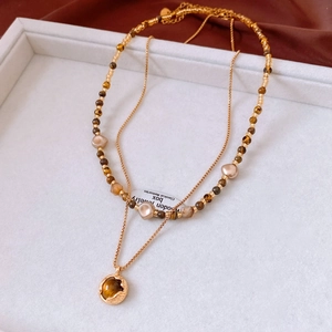 Détail du collier plaqué or 18 carats avec pierre œil de tigre et perles sur soie marron