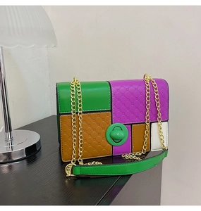 Detail of color-block handbag showing green rotary lock, quilted texture, and gold chain